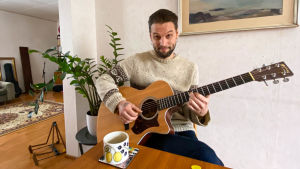 Musikern Frans Anderssons gitarr har inte varit i lika flitigt bruk som tidigare. En man som sitter och spelar gitarr vid matbordet.