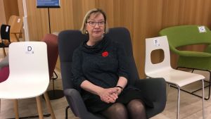 Pirjo Lipasti, här omgiven av stolar, säger att det fattas både små och stora beslut i ett stort projekt. Pirjo Lipasti sitter i en gungstol omgiven av andra stolar.