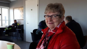 Christina Nygård öppnade en skumvinsflaska när det var klart att Mikko Ollikainen blev invald. Kvinna sitter vid bord med kaffekopp.