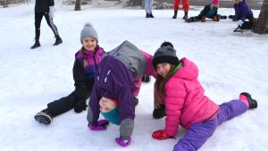 Treorna Vera Broberg, Emma Viileinen och Helmi Vahtera visar upp sina gymnastikkunskaper på rasten - och ettorna tar beundrande efter i bakgrunden. Två flickor gör spagat och en gör brygga, på snöig skolgård.