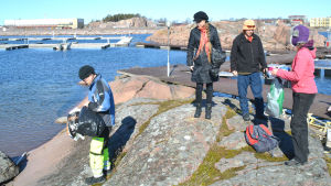 Petri Vartiainen, Heli Katajisto, Simo Nyrönen och Inkeri Pekkanen sprider ut sig över grundet med sina påsar. människor på klippa