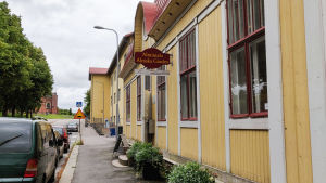 Almska gården byggdes 1910 av bröderna Alm. Den ena brodern drev en cykelbutik i huset medan den andra hade en stor guldsmedsaffär. Ett gult trähus invid en gata. På en skylt står det Almska gården.