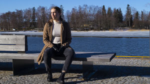 Det var såklart nervöst att rycka in och inte känna mer än en person inom samma enhet. Men Rönnblom växte och utvecklades. Idag vill hon gärna tipsa andra tjejer med samma intresse att våga söka sig till frivillig tjänstgöring. Ung kvinna sitter på bänk vid havet.