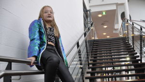 Milla har fått mycket bra respons av vännerna efter att de hört hennes låt. Milla sitter inomhus på ett trappräcke och tittar seriöst in i kameran.