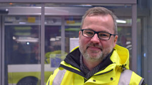 Petri Nissinen är kollektivtrafikplanerare vid HRT. Petri Nissinen poserar i en knallgulrock framför plattform nummer ett i bussterminalen i Mattby.