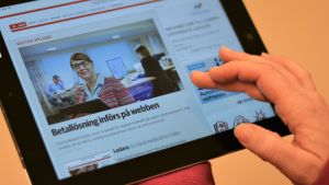De båda tidningarna började ta betalt för sina artiklar på webben för ett drygt år sedan. Hand som scrollar på pekplatta där Västra Nyland syns på skärmen.