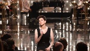 Judy Garland (Renée Zellweger) redo för ännu en show. Judy Garland (Renée Zellweger) sitter på scenkanten och sjunger.