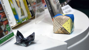 Besökarna fick prova på att vika origami. Konsverkt vikta av papper bland böcker på ett bord.