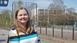 Tiina Ignatius åker gärna tåg, men tycker att det är jobbigt med de låga perrongerna. Tiina Ignatius står vid järnvägsspår i solsken.