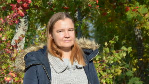 Lotta Björklöf skulle gärna se att mer ull togs tillvara. Lotta Björklund står bredvid buskar vars blad hunnit bli lite röda av höstkylan.