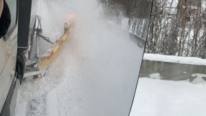 Höga karmar blir sikthinder i trafiken, men en höjbar plog kan skära ner högen lämpligt. En snöplog drar upp en stor snökarm vid sidan om en lastbil.