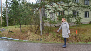 Linda Nic Oireachtaigh visar hur smal vägrenen är strax före bron över Svartsån. Kvinna pekar på vägkanten en regning majdag