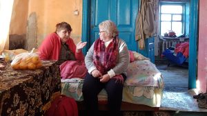 Frivilligarbetare talar med sjuk kvinna i säng