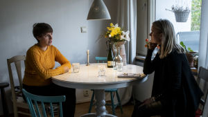 Emma Strömberg tillsammans med Susanne Agte. Emma och Susanne sitter mittemot varann kring ett matbord.