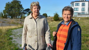 Dorrit Söderblom och Lisbet Tuominen konstaterar att promenadstråket inte är lämpligt för människor med rullator, rullstol eller barnvagn. Dorrit Söderblom och Lisbet Tuominen tittar in i kameran. I bakgrunden skymtar ett bostadshus.