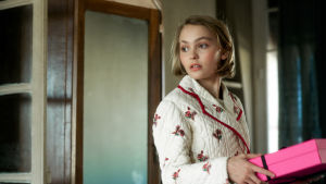 Kate (Lily-Rose Depp) är den blyga systern men också den som får "kontakt". Kate (Lily-Rose Depp) står och håller ett ljusrött paket i handen.