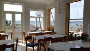 Flera av fönstren i matsalen är ännu täckta av plast. En matsal i ett pensionat vid havet.