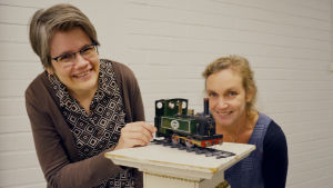 Pia Manns (t.v.), konceptutvecklare med ansvar för BUU-klubbens webbtjänster, och Monica Vikström-Jokela, manusförfattare och regissör, har utgått från tåget när de skapat årets julkalender på buu.yle.fi och på Yle Fem. Pia Manns och Monica Vikström-Jokela vid ett leksakståg.