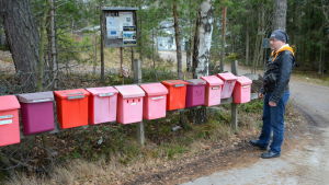 Michael Kiroff skulle gärna återgå till arbetet med att dela ut post. En man står bredvid en lång rad röda postlådor.