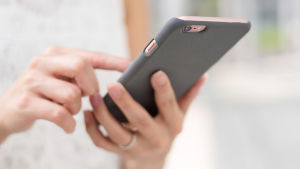Tjänsten ska förkorta de långa telefonköerna. Arkivbild. Kvinna petar på mobiltelefon