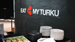 En svart vägg som det står Eat My Turku på, nedanför står tallrikar på ett bord.