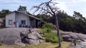 Stugan på gården ska renoveras i vinter. En vit stuga på en klippa vid havet.