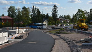 Den här delen av Stora Byvägen har asfalterats den här veckan. Rondellen är nybyggd och till höger byggs anslutningsparkeringen. Längst bort i bild syns hur bilar måste vänta på att få fortsätta köra ut ur rondellen och längs med Stora Byvägen. På bilden syns den delen av Stora Byvägen där den nya rondellen finns.