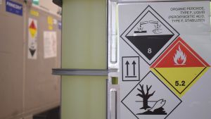 Kemikalier används också då avloppsvattnet renas i reningsverken. En stor tank med grönt innehåll, symboler för giftiga kemikalier på en lapp som sitter på tanken.