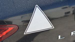 Förutom tio körlektioner i riktig bil kan den blivande föraren också testa sina körkunskaper i en simulator. En vit triangel på bakluckan på en svart bil. Symboliserar att bilen används i trafikskola