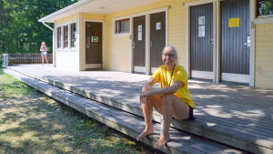 Liinakaisa Taimioja jobbar som strandvakt på Plagen i Lovisa. en kvinlig badvakt på en badstrand sitter framför omklädningsrummen