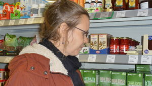 Petra Österberg kollar utbudet i en liten matbutik. Petra Österberg tittar på torkade bönor och linser i en matbutik.