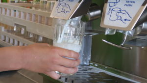 Det dricks fortfarande mycket mjölk i de finländska skolorna. En hand som fyller ett glas med mjölk i en mjölkmaskin