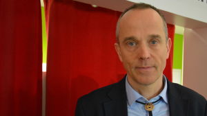 Patrik Henelius, dekanus vid Åbo Akademi. En man står framför ett rött skynke.