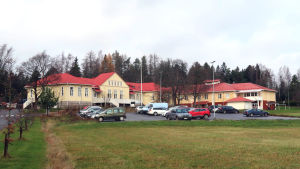 Almahemmets renoveringsbehov utreds på nytt. Almahemmet i Kimito, ett gult stort trähus med en bilparkering framför.