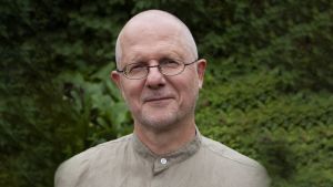 Claus Terlinden har förståelse för att en del blir upprörda av tanken att förnya språket i Bibeln. Själv tycker han ändå att det ska göras, så länge det görs med förstånd och eftertanke. Claus står framför en grönskande bakgrund och ser rakt in i kameran.