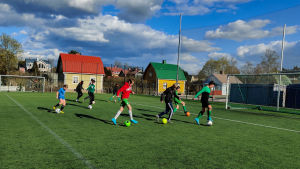 Alla spelare spelar med egen boll och dricker ur egen flaska under träningarna. Ett tiotal pojkar på en konstgräsplan under en fotbollsträning.