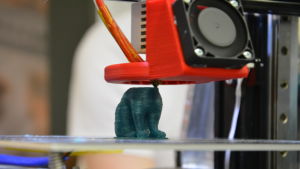 En 3D- printer skapar en hundvalp. En närbild på en 3D- printer som skapar en grön hundvalp.