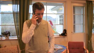 Telefonen ringer ganska ofta när Jan Selenius rör sig ute på fältet. Den här dagen åkte han runt i Snappertuna och lunchen avnjöts i Tunahemmet. En man talar i telefon. Han finns i ett äldreboende (läkare, men civilt klädd)