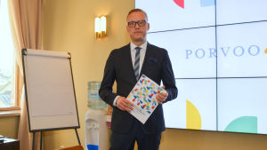 Stadens ekonomi står inför en svår ekvation, säger stadsdirektör Jukka-Pekka Ujula Man håller i en hög papper framför skärm