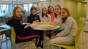 Wilma Grönqvist, Jessica Wikholm, Eloise Melén, Julia Nieminen, Fanny Östergård, Alicia Gustafsson är glada att lasagne stod på dagens meny. Flickor som sitter och äter i en skolmatsal.