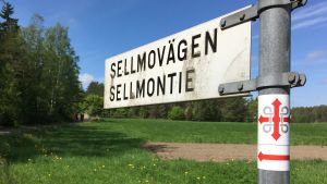 Håll utkik efter S:t Olofs dubbelkors och den röda pilen som visar vägen Märkning av S:t Olofs sjöled på stolpe i Nagu