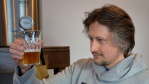 Kim inspekterar glaset med Cowbell. Kim Blomfelt inspekterar sitt hembrygda öl.