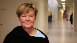 Skolans restriktiva linje har lett till att elever dricker mindre energidrycker, menar rektor Tanja Koivisto i Hangö högstadium. Rektorn för Hangö högstadium står i en tom skolkorridor och ser mot kameran.