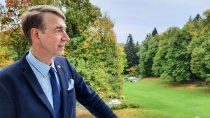 Haiko Gårds vd Juha Mähönen tittar ut över parken. En man står på en balkong och tittar ut över en trädgård.