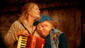 Anna Bjelkerud och Christian Andrén i Johannes Nyholms Jätten, 2016. Filmen belönades med tre guldbaggar. Bild på mor och son sittande tätt intill varandra med ett dragspel i förgrunden.
