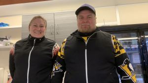 Jonne Korpela säljer delikatesser på torget. Inne i vagnen är det lätt att hålla sig varm. Kvinna och Man står tillsammans i matförsäljningsvagn på torget.