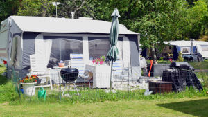 En del satsar på mycket utegrejer. Husvagn med bord, grill,s taket och andra grejer framför.