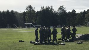 De senaste två åren har fem brigader testat olika nya utbildningsformer och från och med nästa år ska den nya beväringsutbildningen införas på alla brigader. Beväringar står och pratar på en stor gräsplan.