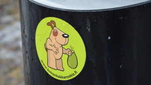 Här kan man slänga hundbajset! Skräpkorg för hundbajs, med ett koirankakka- klistermärke.