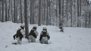 I vita kamouflagedräkter rör sig beväringarna under övningen i Galoppskogen i Ekenäs. Tre beväringar under en skogsövning i Galoppskogen i Raseborg.
